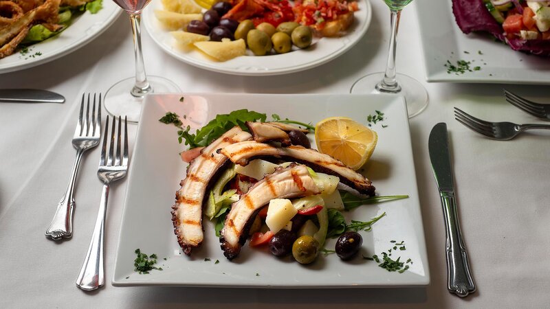 Grilled octopus on top of salad